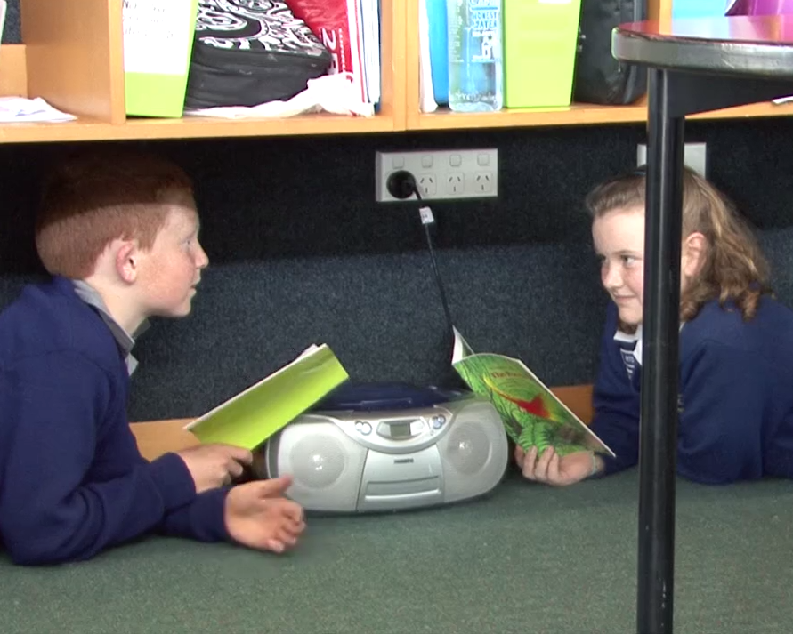 Students reading under bookshelves