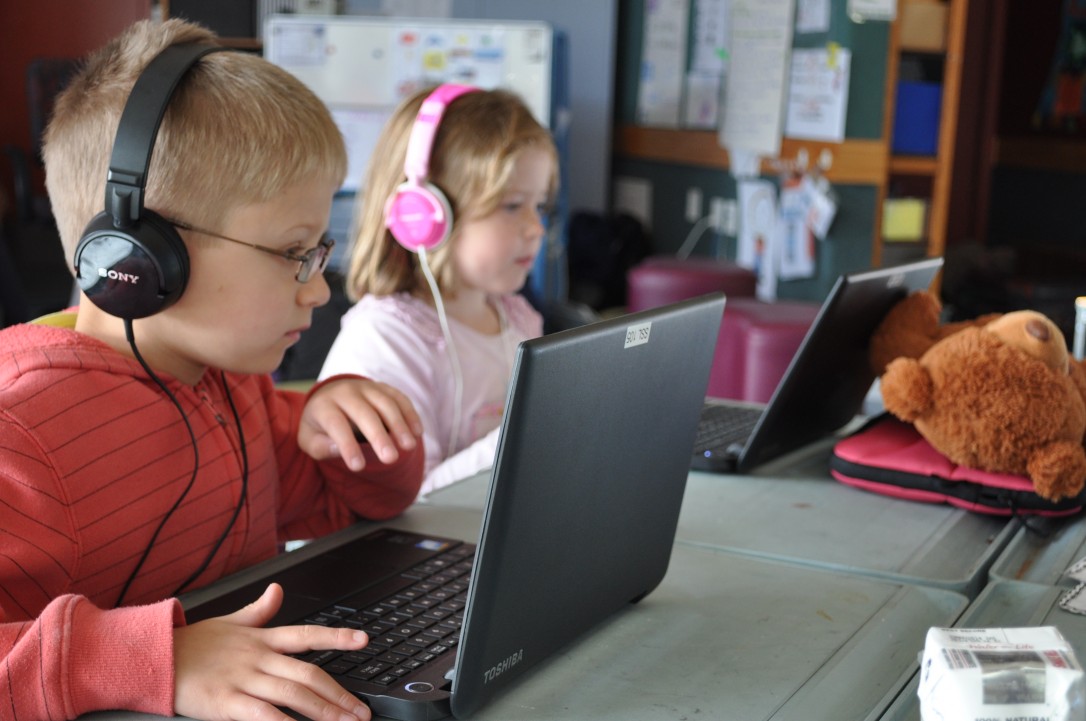 students on laptops using headphones