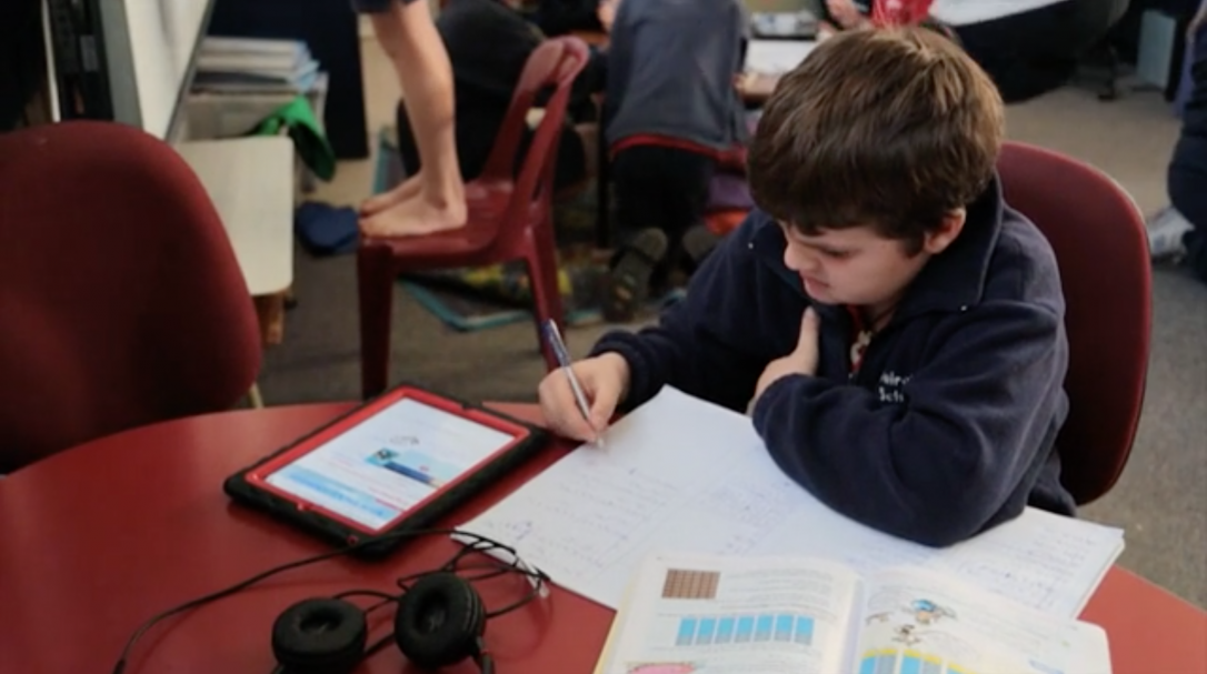 student planning work with ipad, pen, and paper